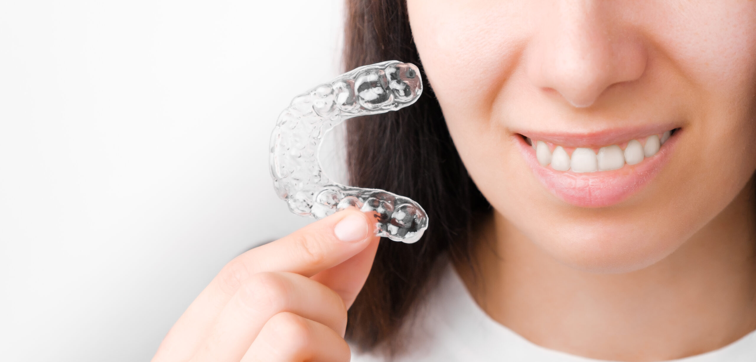 Woman holding clear aligners with smile